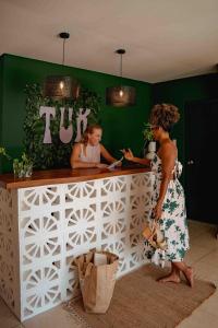 威廉斯塔德TUK Tropical Boutique Resort Jan Thiel的两名妇女站在酒吧的柜台上
