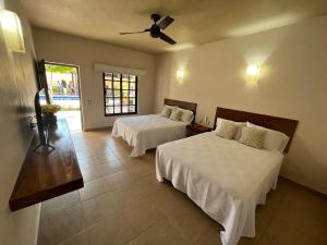 锡瓦塔塔内霍Natura Hotel & Villas的一间卧室配有两张床和吊扇