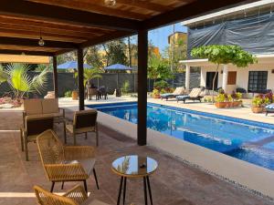 锡瓦塔塔内霍Natura Hotel & Villas的房屋旁的游泳池配有椅子和桌子