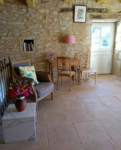 Sainte-Eulalie-dʼAnsLes Fleurs d'Ans的客厅配有桌椅和石墙
