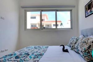蓬塔卡纳BAVARO PUNTA CANA Apartamento con Piscina的一间卧室设有一张床,窗户上装有猫