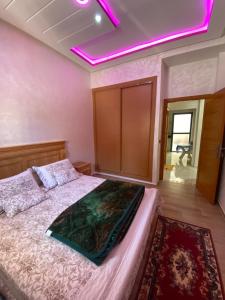 布兹尼盖Bouznika的一间卧室配有一张带紫色灯的天花板床。