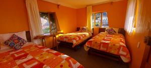 奥科苏尤Musiña Lodge的配有橙色墙壁和窗户的客房内的两张床