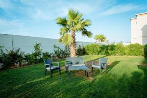 阿加迪尔Villa 10 Palmeraie Golf Agadir的棕榈树前的三把椅子和一张桌子