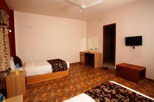 奇旺Sauraha Holiday Home Riverside的酒店客房设有两张床和一台平面电视。