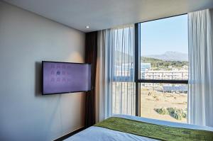 西归浦市Jeju Pureun Hotel的卧室设有大窗户和墙上的电视。