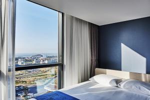 西归浦市Jeju Pureun Hotel的一间卧室设有一张床和一个大窗户