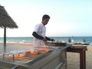 尼拉瓦利NN Beach Resort & SPA的海滩上的烧烤人烹饪食物