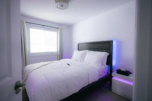 尼亚加拉瀑布5 BEDS On The Rapids - 5 Mins To The Falls的一间卧室配有白色床和紫色照明