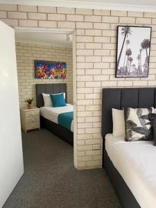 North WollongongBeach Park Motel的一间卧室设有两张床和砖墙