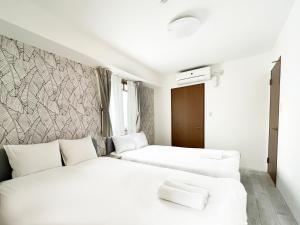 大阪Dio Higashi Shinsaibashi的配有白色墙壁的酒店客房内的两张床