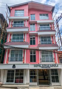 大吉岭Hotel Sonar Bangla Darjeeling的粉红色的建筑,前面有标志