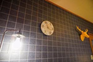 别府Living CUBE Beppu的蓝瓷砖墙上的时钟,灯