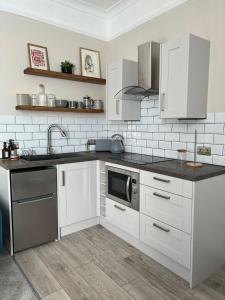 布莱顿霍夫Norton house的厨房配有白色橱柜、水槽和微波炉