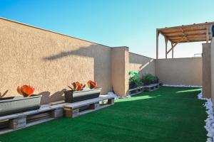 维多利亚Anici Crt Penthouse 4 - with private rooftop pool的一个带长椅和草地的庭院,毗邻墙壁