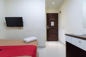 巴淡岛中心邦加拉亚街红门旅馆的一间设有床铺和墙上电视的客房