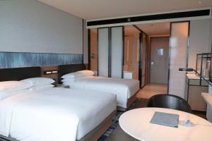 广州Guangzhou Marriott Hotel Nansha的酒店客房设有两张床和一张桌子。