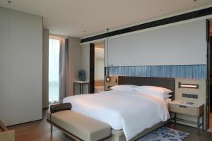 广州Guangzhou Marriott Hotel Nansha的卧室配有一张白色大床和一把椅子