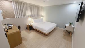 釜山Hotel Andrest的卧室配有白色的床、书桌和桌子