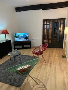 迪南EGLANTINE 14 APPARTEMENT CENTRE HISTORIQUE DE DINAN的客厅配有两把椅子和电视