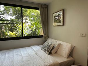 曼谷Cozycomo Bangkok的一间卧室设有一张床和一个大窗户