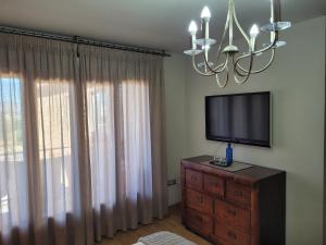 格拉纳达Privada Confort Granada的客厅配有带吊灯的梳妆台上的电视