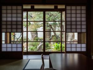 出云市Nipponia Izumo Hirata Cotton Road的客房设有桌子和大窗户。