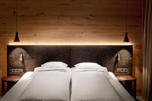 莱赫阿尔贝格奥尤恩霍夫酒店的卧室内的两张床,墙上有两盏灯