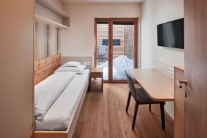 莱赫阿尔贝格Hotel Sonnblick的酒店客房配有一张床、一张书桌和一张书桌。