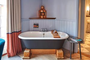 浦耳普尔酒酒店的带浴缸的浴室,提供一瓶啤酒