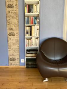 米卢斯King size lounge 76m2 de confort au centre ville的书架前的皮椅,书架上摆放着书籍