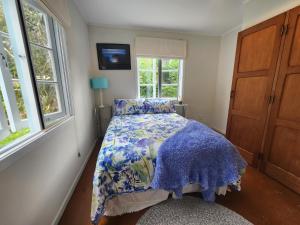 凯里凯里La Petite Ferme Manor Kerikeri的一间卧室配有一张带蓝色棉被的床和窗户。