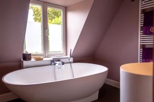 布鲁日Saint Georges Bruges Luxury Suites的带窗户的浴室内的白色浴缸