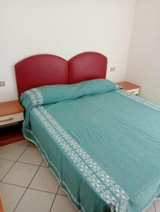 里米尼Appartamenti Carlotta的一张带绿色棉被和红色床头板的床