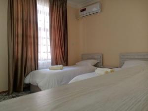 撒马尔罕Istirohat guest house的酒店客房设有三张床和窗户。