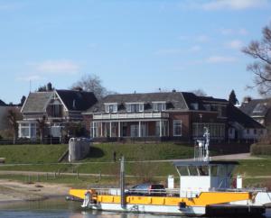 迪伦Aan Het Veer minimaal 4 overnachtingen的船屋前水面上的黄色船