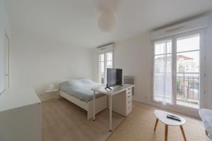 布西圣乔治PARIS-DISNEY - STUDIO 1 MIN GARE的白色卧室配有一张床和一张书桌上的电视