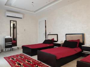 索瓦马The Legend Villa فيلا الاسطوره的一间卧室配有两张带红色床单和地毯的床。