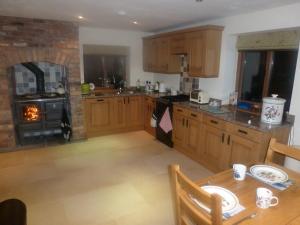南特威奇Mile House Barn Bed & Breakfast的厨房配有木制橱柜、桌子和烤箱。