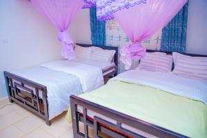 MbaleJ & A VILLAS的配有粉红色窗帘的客房内的两张床