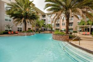 休斯顿Resort-style Pool, Gym/Garage, 1Br, Medical Center的一座大型游泳池,在一座建筑前种有棕榈树