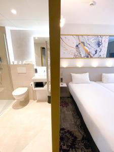 梅里尼亚克布里特酒店波尔多机场勒索雷泰尔店的一间卧室配有一张床,浴室设有卫生间