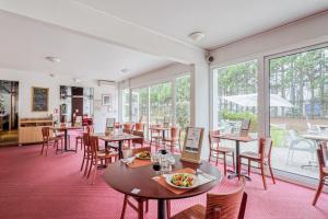 梅里尼亚克布里特酒店波尔多机场勒索雷泰尔店的餐厅设有桌椅和窗户。