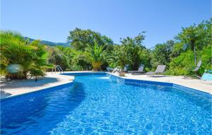 Petreto-BicchisanoNice Home In Petreto Bicchisano With Heated Swimming Pool的一个带椅子和树木的蓝色游泳池