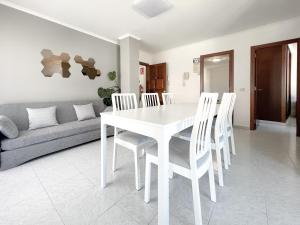 拉科萨Apartamentos Xulia的白色的用餐室配有白色的桌椅
