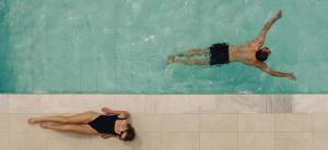 帕福斯Regency Boutique Hotel Holiday Suites的男女在游泳池游泳