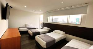 波哥大Hotel Expo Hotel Ferial的酒店客房设有三张床和窗户。