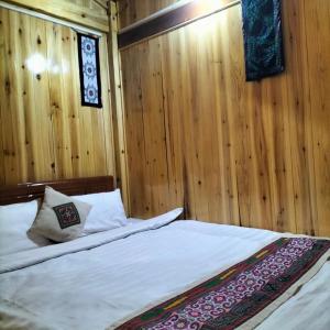 萨帕Sapa Shalom Homestay的一间卧室配有一张带木墙和木地板的床。