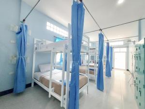 考索Khao Sok Backpacker Hostel的一间设有四张双层床和蓝色窗帘的房间