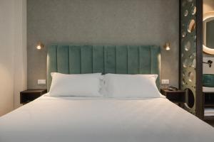 里乔内Hotel Sole的一张配有白色床单和绿色床头板的大床